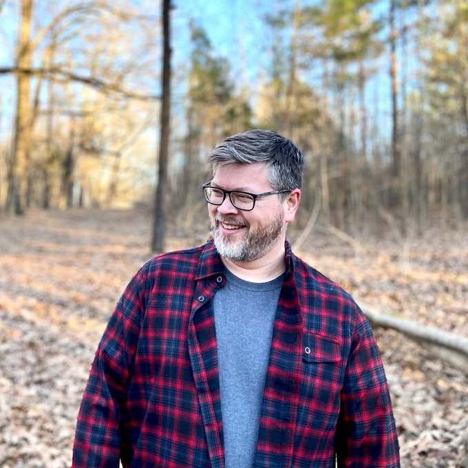 John Albert Thomas smiling and walking through the woods